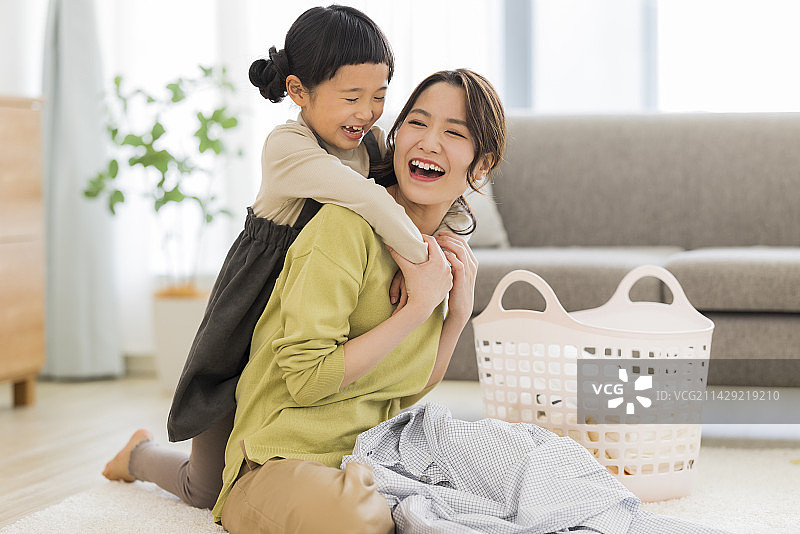 女孩拥抱正在叠衣服的母亲图片素材