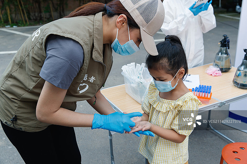 社区志愿者给小女孩用酒精消毒图片素材