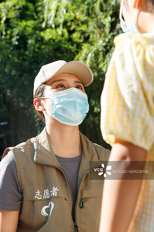 社区志愿者帮小女孩戴口罩图片素材