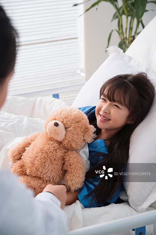 年轻女医生给病床上的小女孩检查身体图片素材