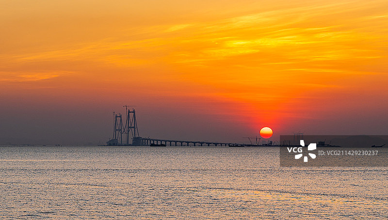 从深圳西湾红树林公园远眺建设中的深中通道跨海大桥和日落图片素材