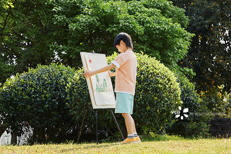 在草坪上画画的小男孩图片素材