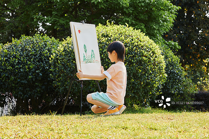 在草坪上画画的小男孩图片素材