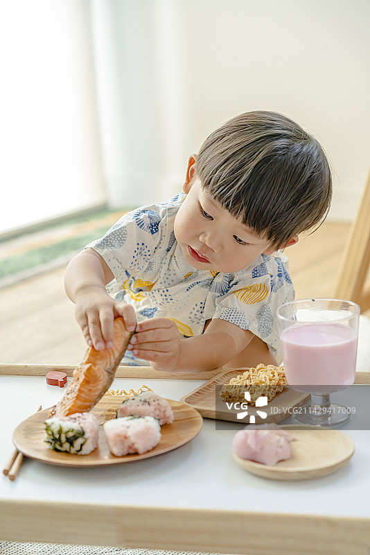 享受西瓜饭团三文鱼美食的可爱花样男孩图片素材