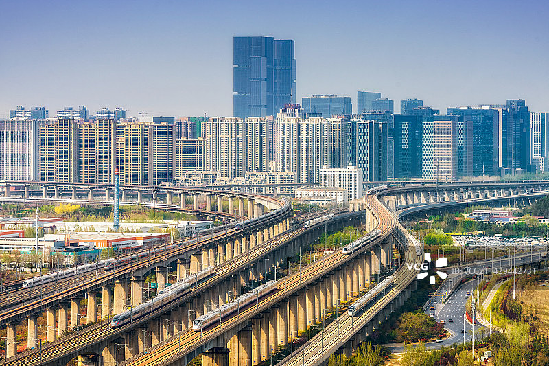 郑州京广高铁、郑渝高铁、郑阜高铁、机场快线等四通八达的高铁网络综合枢纽与城市天际线春季户外风光高视角图片素材