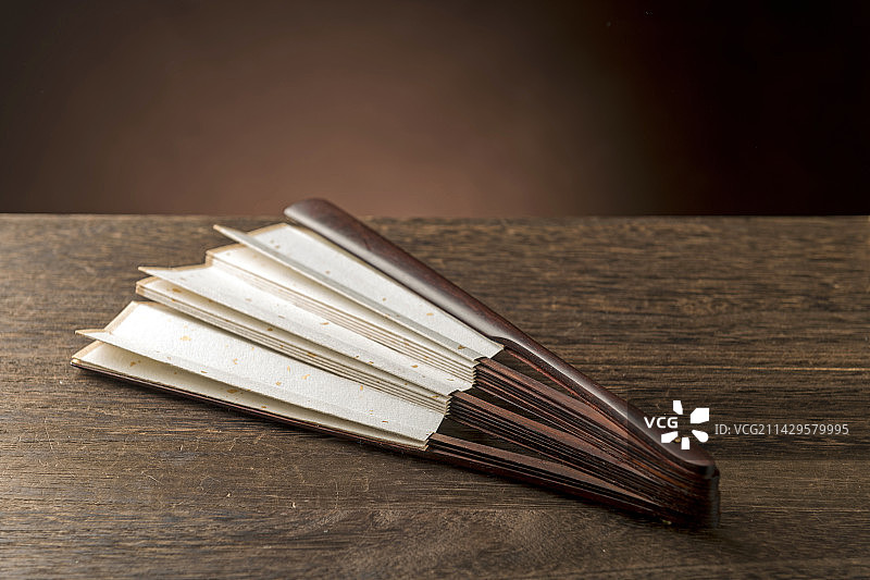 一把中国传统折扇纸扇摆放在桌面上特写图片素材