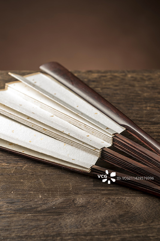 一把中国传统折扇纸扇摆放在桌面上特写图片素材