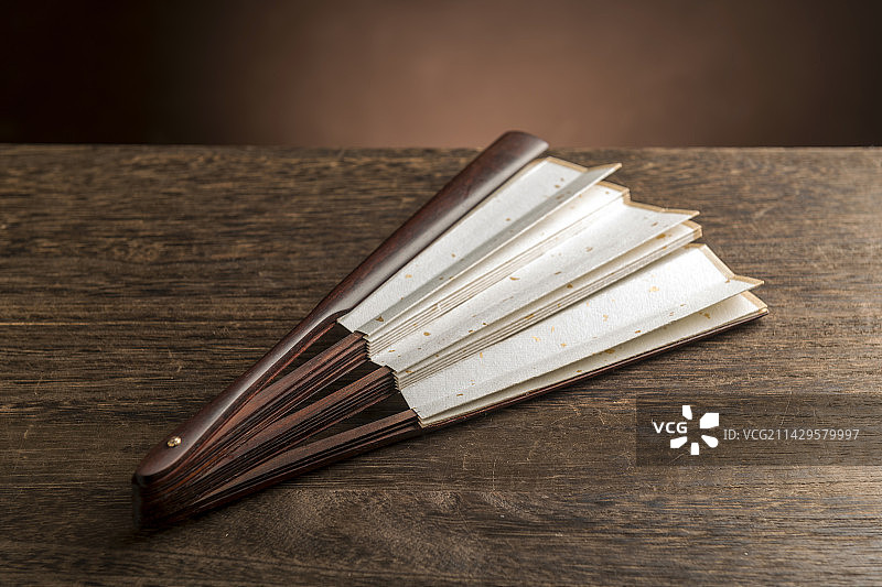 一把中国传统折扇纸扇摆放在桌面上特写图片素材