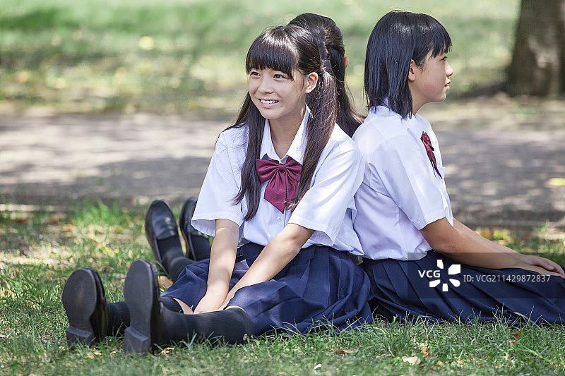 在球场上背靠背坐着的初中生图片素材