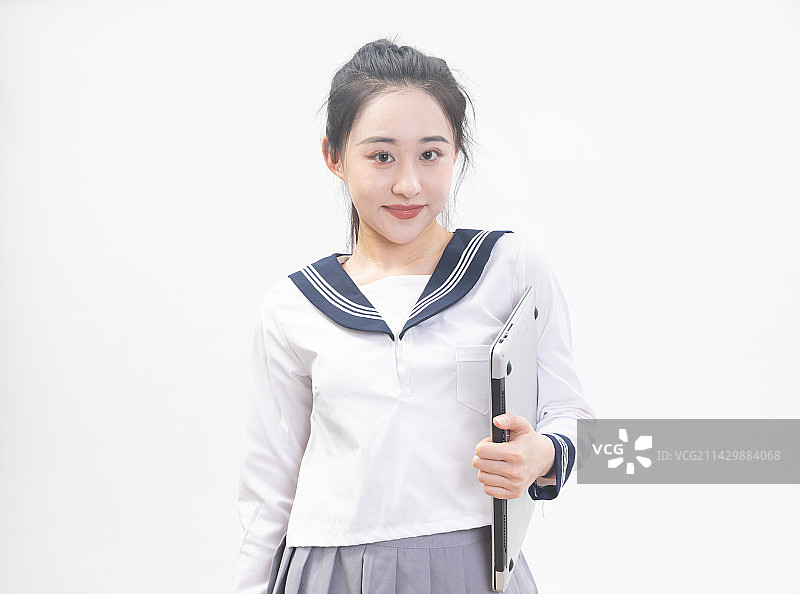 白背景前拿着笔记本电脑的青年女学生半身肖像图片素材