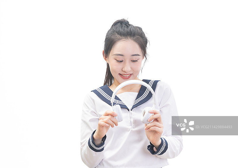 白背景前带着耳机穿学生服的青年女学生图片素材