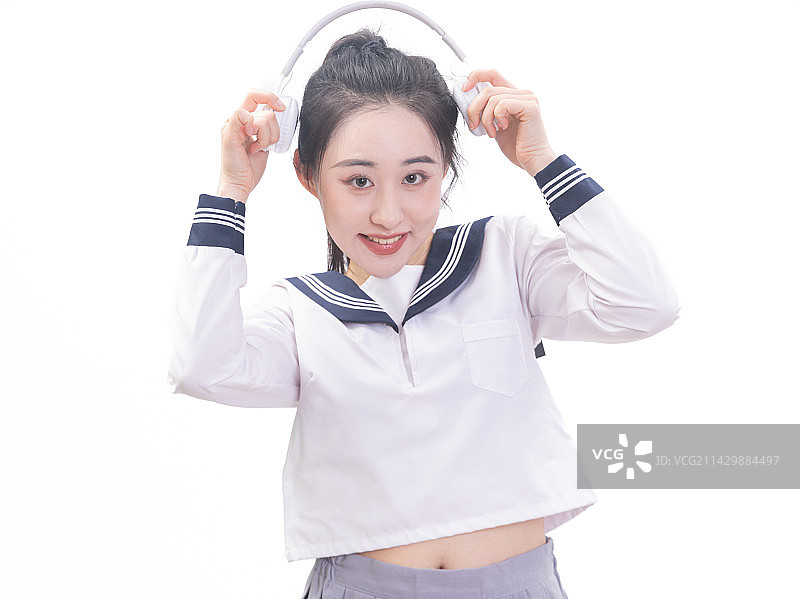 白背景前带着耳机穿学生服的青年女学生图片素材
