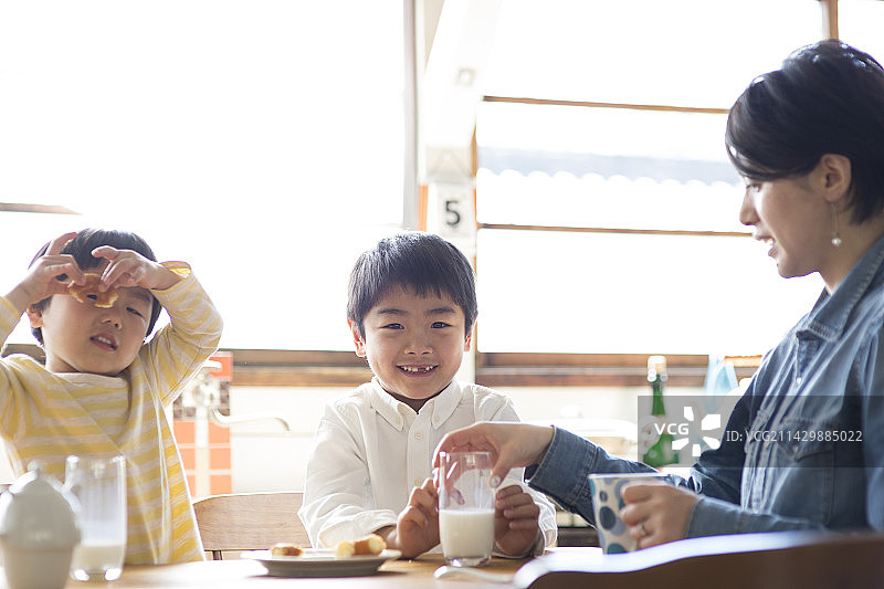 兄妹和母亲在厨房餐桌旁吃零食图片素材