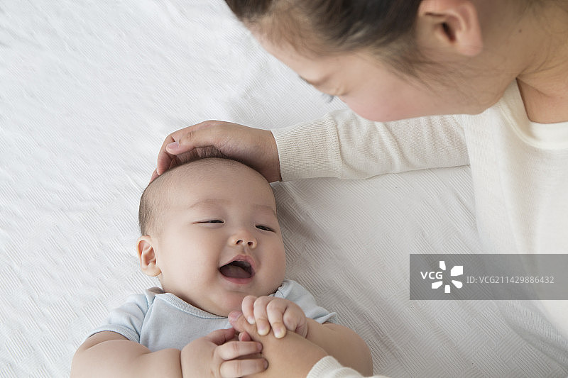 母亲抚摸着微笑的婴儿的头部图片素材