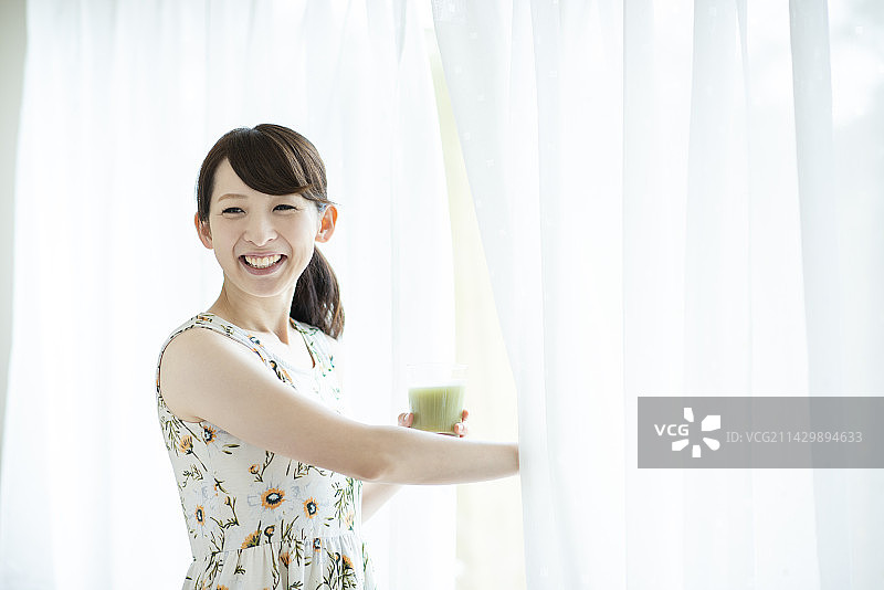 女人拿着冰沙并拉开窗帘图片素材