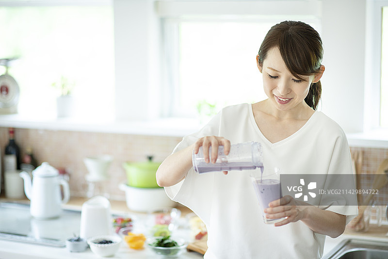 女人在厨房里倒思慕雪图片素材