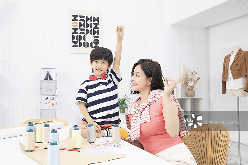 坐在工作室桌子上的小男孩与母亲互动交流图片素材