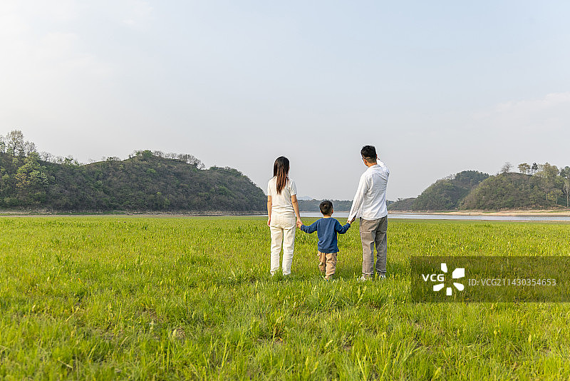 春天山脉湖泊草坪上牵手的一家三口人图片素材