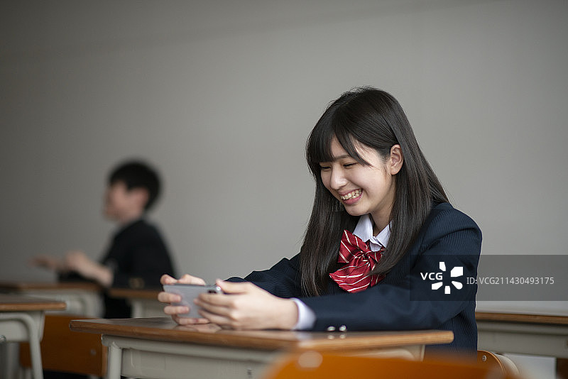 女学生在教室里看她的智能手机图片素材