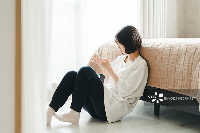 坐在房间里玩手机的女人图片素材