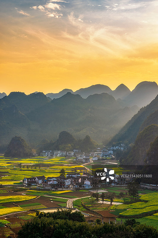 贵州省黔西南布依族苗族自治州兴义市万峰林景区下纳灰村油菜花田与喀斯特地貌春季户外黄昏日落高视角图片素材