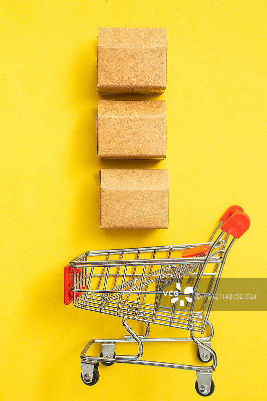 黄色背景中的购物车和快递盒图片素材
