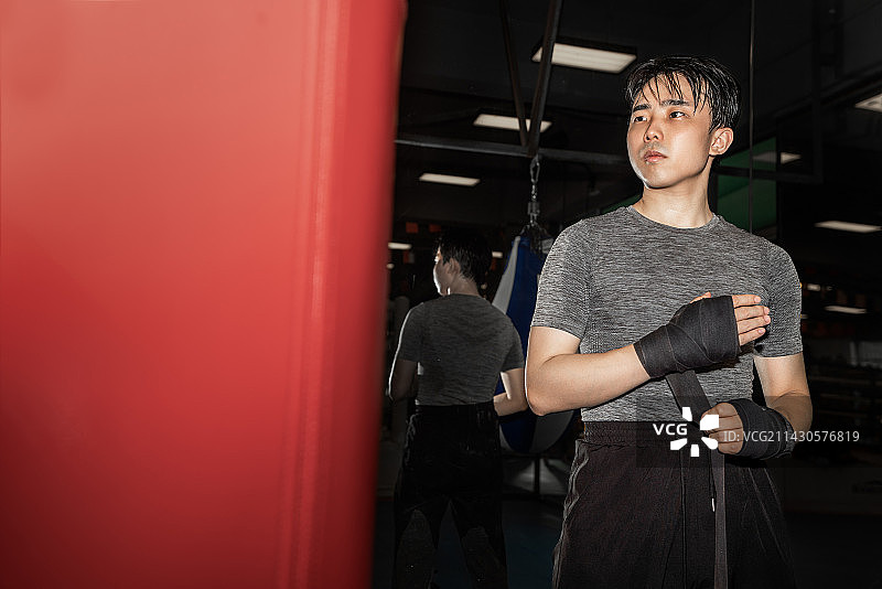 亚洲运动男性正在拳馆内缠拳击绷带图片素材