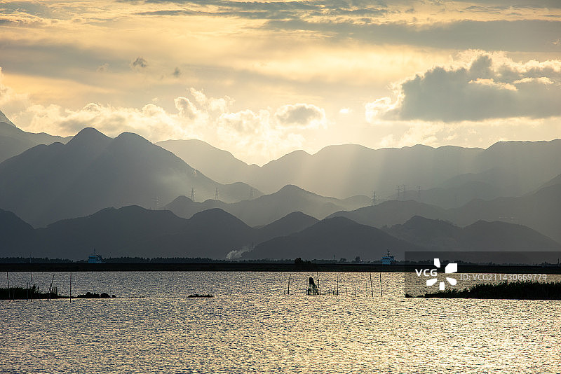 平静湖面远方的山川丘陵起伏地形图片素材