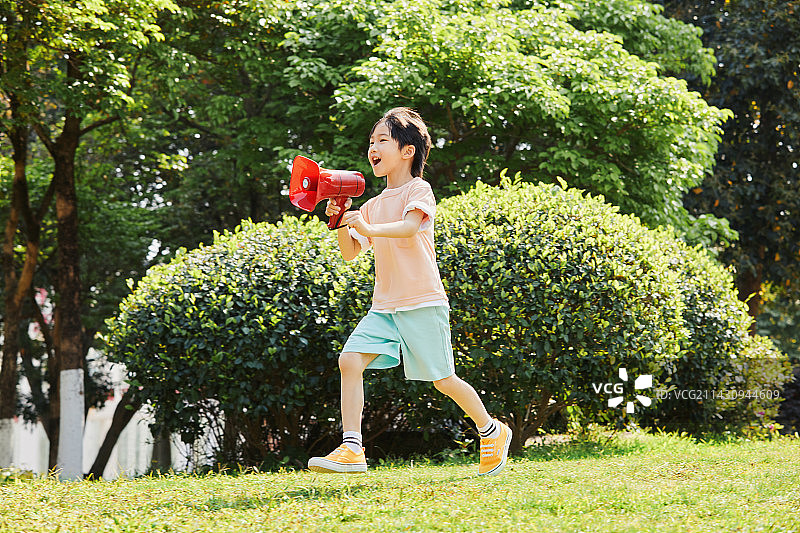 手拿话筒在草地上奔跑的小男孩图片素材