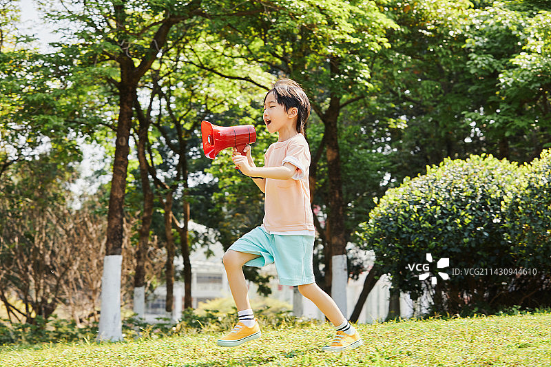 手拿话筒在草地上奔跑的小男孩图片素材