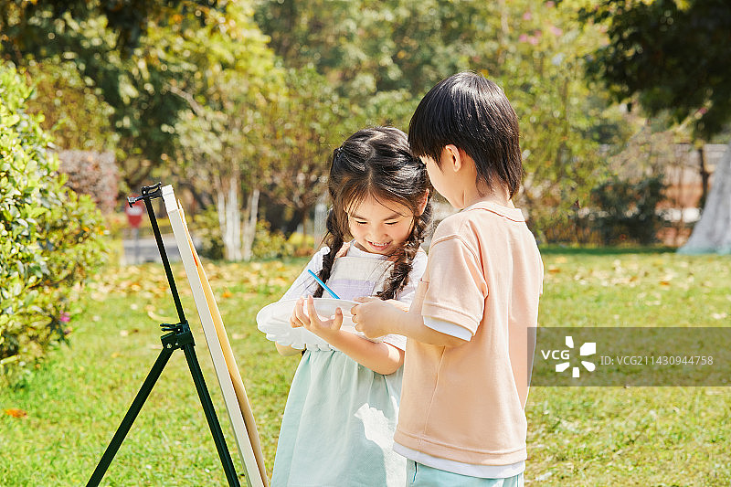 在草坪上画画的兄妹图片素材