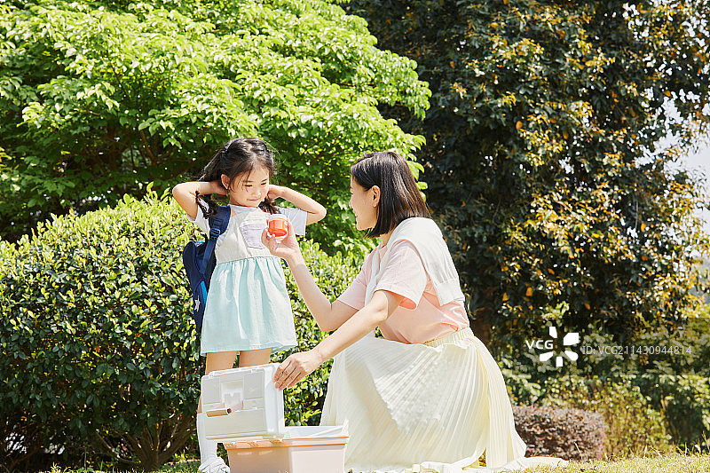 蹲在草坪上与女儿交流的年轻妈妈图片素材