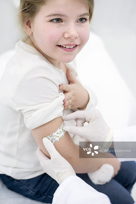 医生给注射后的女孩手臂贴上膏药图片素材