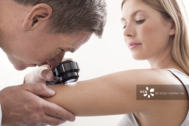 医生检查年轻女子手臂上的痣图片素材