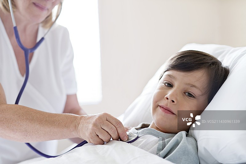 在病床上，护士用听诊器的男孩图片素材