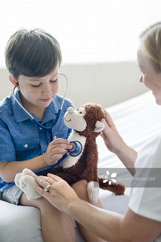 男孩玩听诊器和泰迪熊图片素材