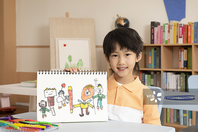 坐在桌子前画画学习的小男孩图片素材