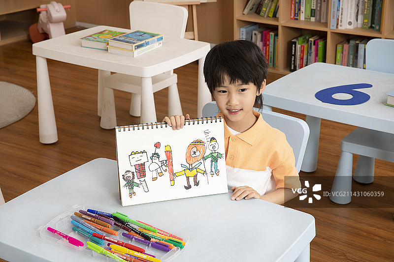 坐在桌子前画画学习的小男孩图片素材