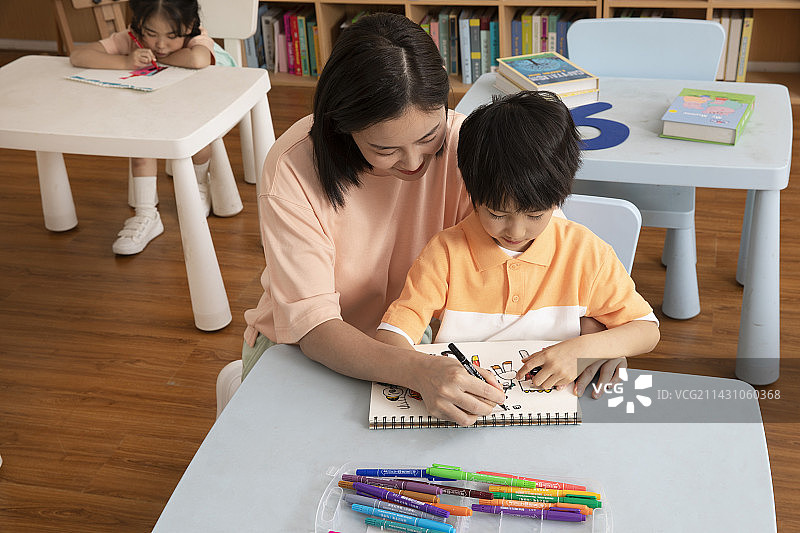 教男孩画画的年轻女老师图片素材