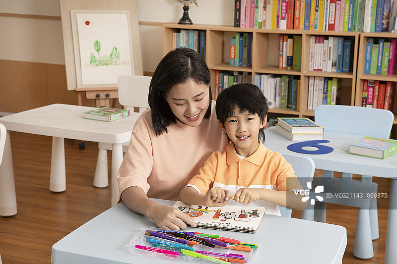 辅导男孩画画的女老师图片素材