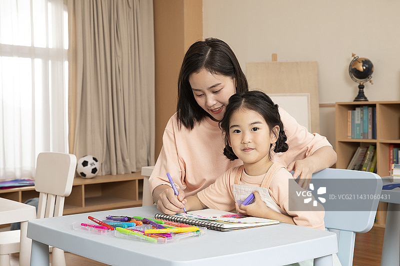 辅导女孩画画写字的年轻老师图片素材