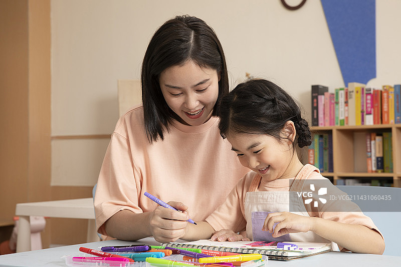辅导女孩画画写字的年轻老师图片素材