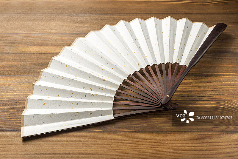 一把折扇纸扇摆放在木桌面上特写图片素材
