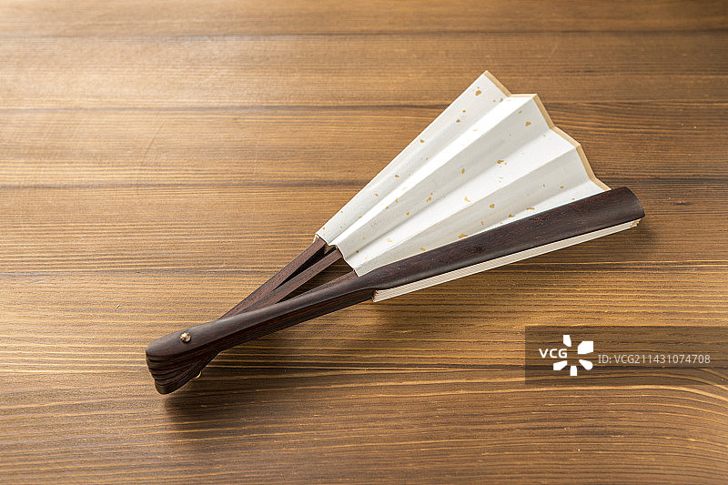 一把折扇纸扇摆放在木桌面上特写图片素材