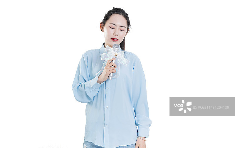 使用麦克风快乐唱歌的蓝色衬衣年轻女孩图片素材