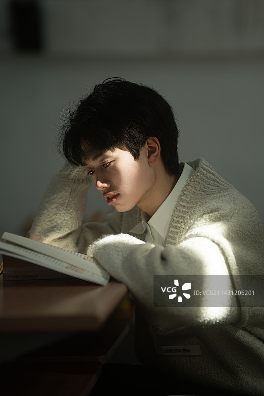年轻男子坐在学校看书图片素材