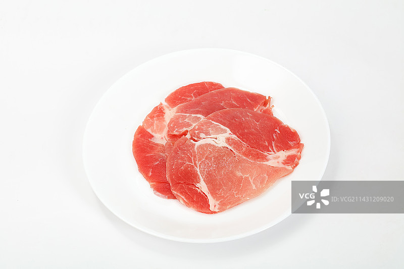 盘子里的三片黑猪肉片，摆放在白色背景上图片素材