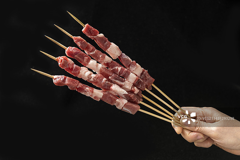 一盘烤羊肉串摆放在木桌面上特写图片素材