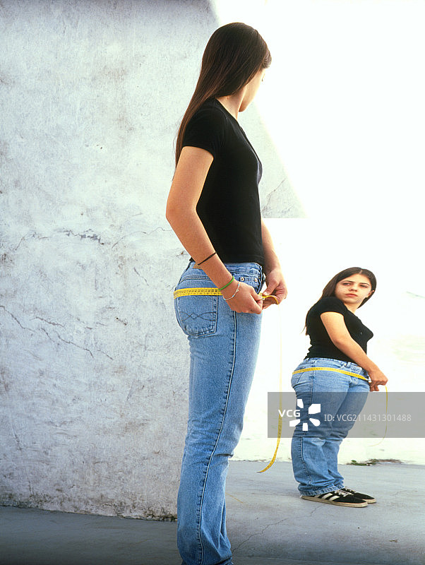 在镜子前测量身材的厌食症少女图片素材