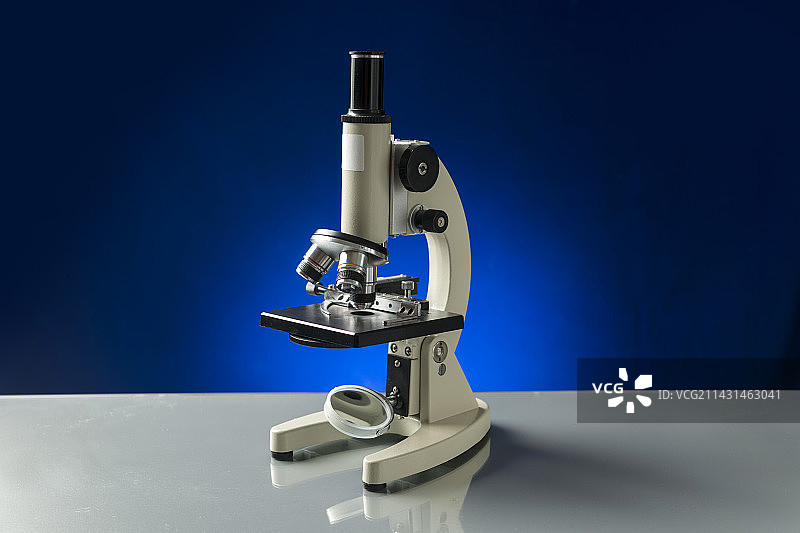 光学仪器显微镜摆放在桌面上特写蓝色背景图片素材